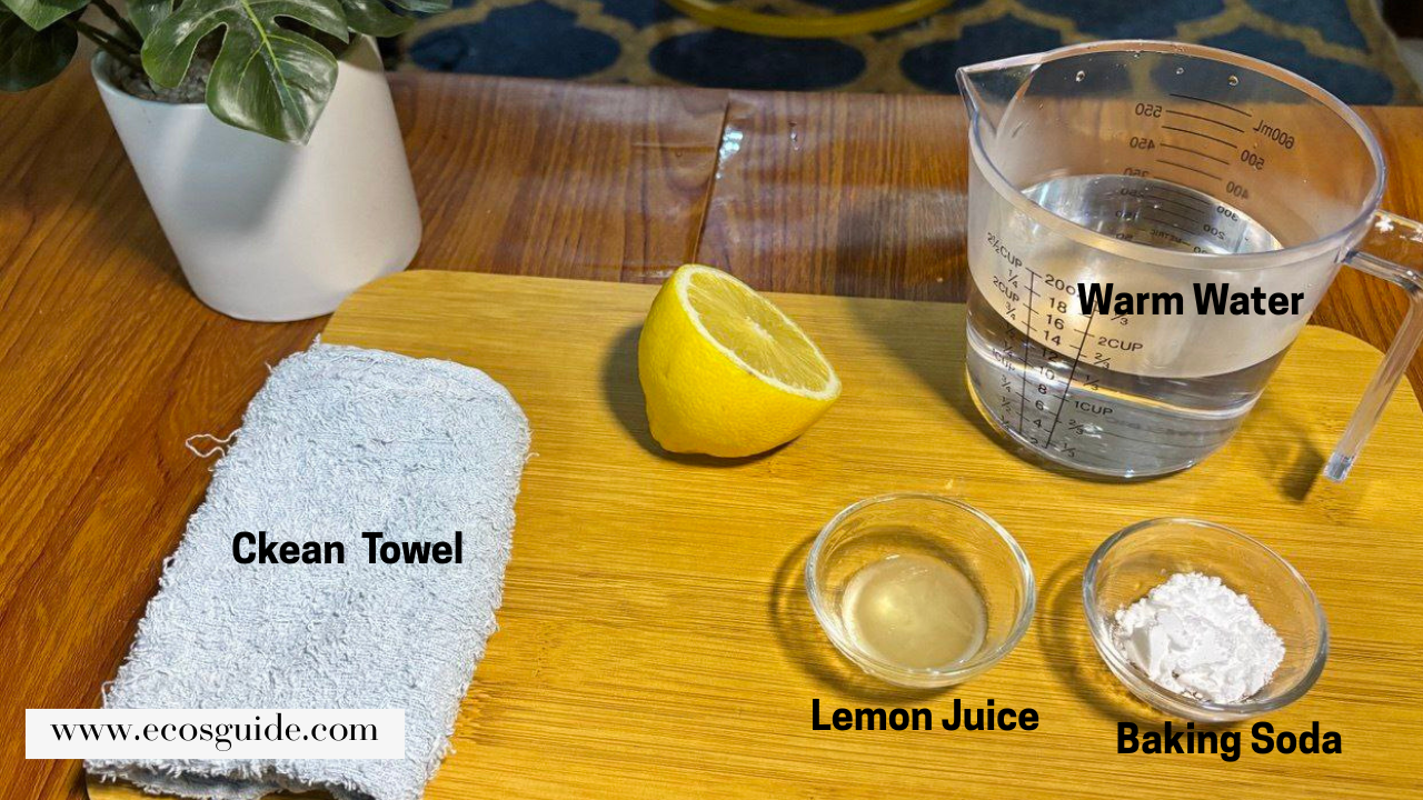 Lemon half, warm water, baking soda, and towel arranged on a wooden surface for cleaning preparation.