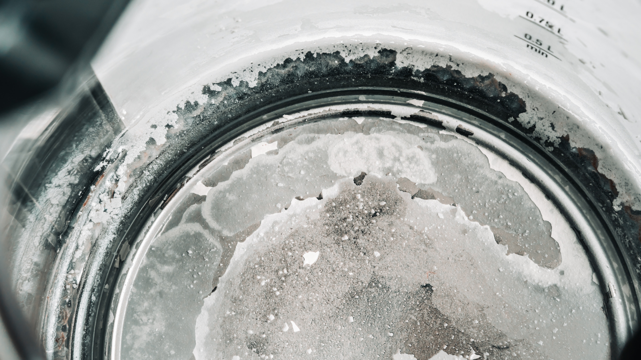 Severe Limescale Inside Kettle Heavy limescale buildup coating the interior of a stainless steel kettle.