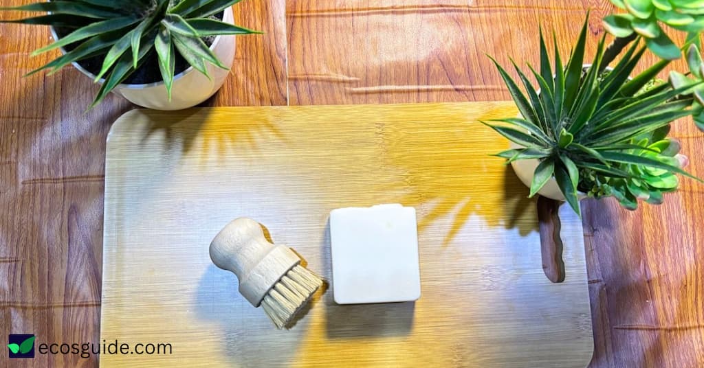 Dish soap bar and bamboo dish brush on a wooden board for zero waste dishwashing
