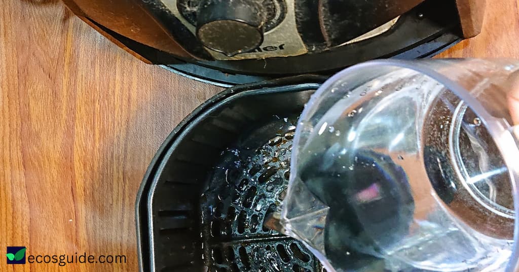 pouring warm water into an air fryer basket to soak
